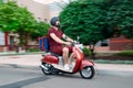 Delivery boy wearing red uniform on scooter with isothermal food case box driving fast. Express food delivery service