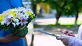 Delivery company client appending signature on tablet and receiving flowers