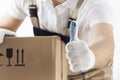 Delivery concept. Courier holds his thumb up. Man with cardboard box close-up. Relocation services. Loader with a box Royalty Free Stock Photo