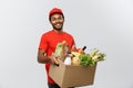 Delivery Concept - Handsome African American delivery man carrying package box of grocery food and drink from store