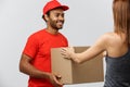 Delivery Concept - Handsome African American delivery man giving package to homeowner. Isolated on Grey studi Royalty Free Stock Photo