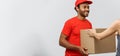 Delivery Concept - Handsome African American delivery man giving package to homeowner.  on Grey studio Royalty Free Stock Photo