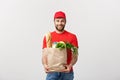 Delivery Concept - Handsome Cacasian delivery man carrying package bag of grocery food and drink from store. Isolated on Royalty Free Stock Photo