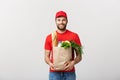 Delivery Concept - Handsome Cacasian delivery man carrying package bag of grocery food and drink from store. Isolated on Royalty Free Stock Photo