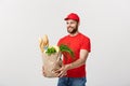 Delivery Concept - Handsome Cacasian delivery man carrying package bag of grocery food and drink from store. Isolated on Royalty Free Stock Photo