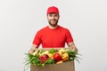 Delivery Concept - Handsome Cacasian delivery man carrying package box of grocery food and drink from store. Isolated on Royalty Free Stock Photo