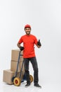 Delivery Concept - Portrait of Handsome African American delivery man or courier pushing hand truck with stack of boxes Royalty Free Stock Photo