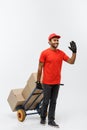 Delivery Concept - Portrait of Handsome African American delivery man or courier pushing hand truck with stack of boxes Royalty Free Stock Photo