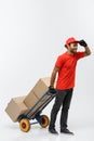 Delivery Concept - Portrait of Handsome African American delivery man or courier pushing hand truck with stack of boxes Royalty Free Stock Photo