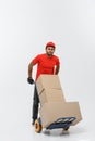 Delivery Concept - Portrait of Handsome African American delivery man or courier pushing hand truck with stack of boxes Royalty Free Stock Photo