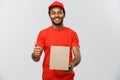 Delivery Concept - Portrait of Happy African American delivery man holding a box package and showing thumps up. Isolated Royalty Free Stock Photo