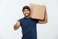 Delivery Concept - Portrait of Happy African American delivery man holding a box package and showing thumps up. Isolated Royalty Free Stock Photo