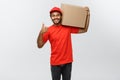 Delivery Concept - Portrait of Happy African American delivery man holding a box package and showing thumps up. Isolated Royalty Free Stock Photo