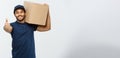 Delivery Concept - Portrait of Happy African American delivery man holding a box package and showing thumps up. Isolated Royalty Free Stock Photo