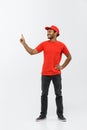 Delivery Concept - Portrait of Happy African American delivery man pointing hand to present something. Isolated on Grey Royalty Free Stock Photo