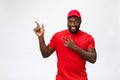 Delivery Concept - Portrait of Happy African American delivery man pointing hand to present something. Isolated on Grey Royalty Free Stock Photo