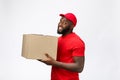 Delivery Concept - Side view Portrait of Happy African American delivery man in red cloth holding a box package Royalty Free Stock Photo