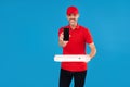 Delivery Concept. Smiling delivery man or courier with pizza box showing mobile phone to customer to check the order. Blue studio Royalty Free Stock Photo