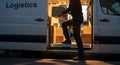 Delivery driver loading cardboard boxes into a white logistics van for distribution Royalty Free Stock Photo