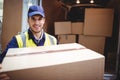 Delivery driver smiling at camera by his van holding parcel