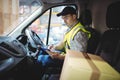Delivery driver using tablet in van with parcels on seat Royalty Free Stock Photo