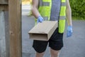 Delivery driver wearing rubber gloves handing over a parcel