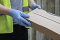 Delivery driver wearing rubber gloves handing over a parcel