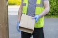 Delivery driver wearing rubber gloves handing over a parcel