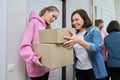 Delivery of goods, two women with cardboard boxes near front door of house