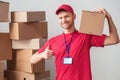 Delivery guy isolated on white wall standing holding box on shoulder looking camera happy showing thumb up Royalty Free Stock Photo