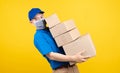 Delivery handsome man wearing mask with heavy many carton box picking up the package