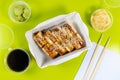 Delivery of Japanese food. Roll with smoked eel, pickled ginger and sesame. Bright green background. Chinese chopsticks Royalty Free Stock Photo