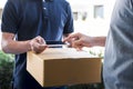 Delivery mail man giving parcel box to recipient, Young man appending signing in digital mobile phone receipt of delivery package