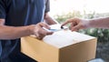 Delivery mail man giving parcel box to recipient, Young man appending signing in digital mobile phone receipt of delivery package