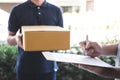 Delivery mail man giving parcel box to recipient, Young man signing receipt of delivery package from post shipment courier at home