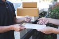 Delivery mail man giving parcel box to recipient, Young man signing receipt of delivery package from post shipment courier at home