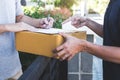 Delivery mail man giving parcel box to recipient, Young man signing receipt of delivery package from post shipment courier at home