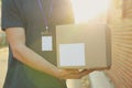 Delivery man with badge holds blank box outdoor