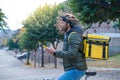 Delivery man on bike looking GPS location in the phone. Black courier delivering food and drink.