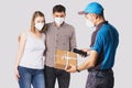 Delivery man in blue uniform brought a box package to a beautiful young couple , holding the mobile phone in his hand Royalty Free Stock Photo