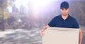 Delivery man with box against blurry street with flare Royalty Free Stock Photo