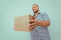 Delivery man with brown box on your home door. Light blue background. Hands hold parcel. Delivery service. Royalty Free Stock Photo