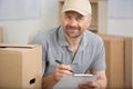 delivery man with cardboard box checking address list