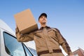 Delivery Man Carrying Cardboard Box On Shoulder Against Sky Royalty Free Stock Photo