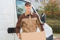 Delivery Man Carrying Cardboard Box With Truck In Background Royalty Free Stock Photo