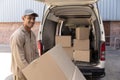 Delivery man carrying cardboard boxes on trolley near van outside the warehouse Royalty Free Stock Photo