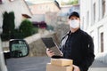 Delivery man courier with face mask delivering parcel box in town. Royalty Free Stock Photo