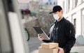 Delivery man courier with face mask delivering parcel box in town. Royalty Free Stock Photo