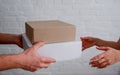 Delivery. Man courier hands over cardboard boxes to woman. Close-up on hands. White brick wall background Royalty Free Stock Photo