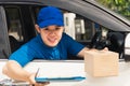 Delivery man courier wear uniform in the car hold documents clipboard hand over to customer to signing Royalty Free Stock Photo